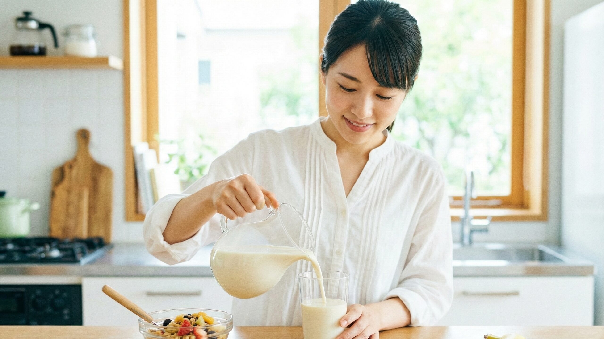 朝食時に手軽に鉄分を補える豆乳をコップに注ぐ女性