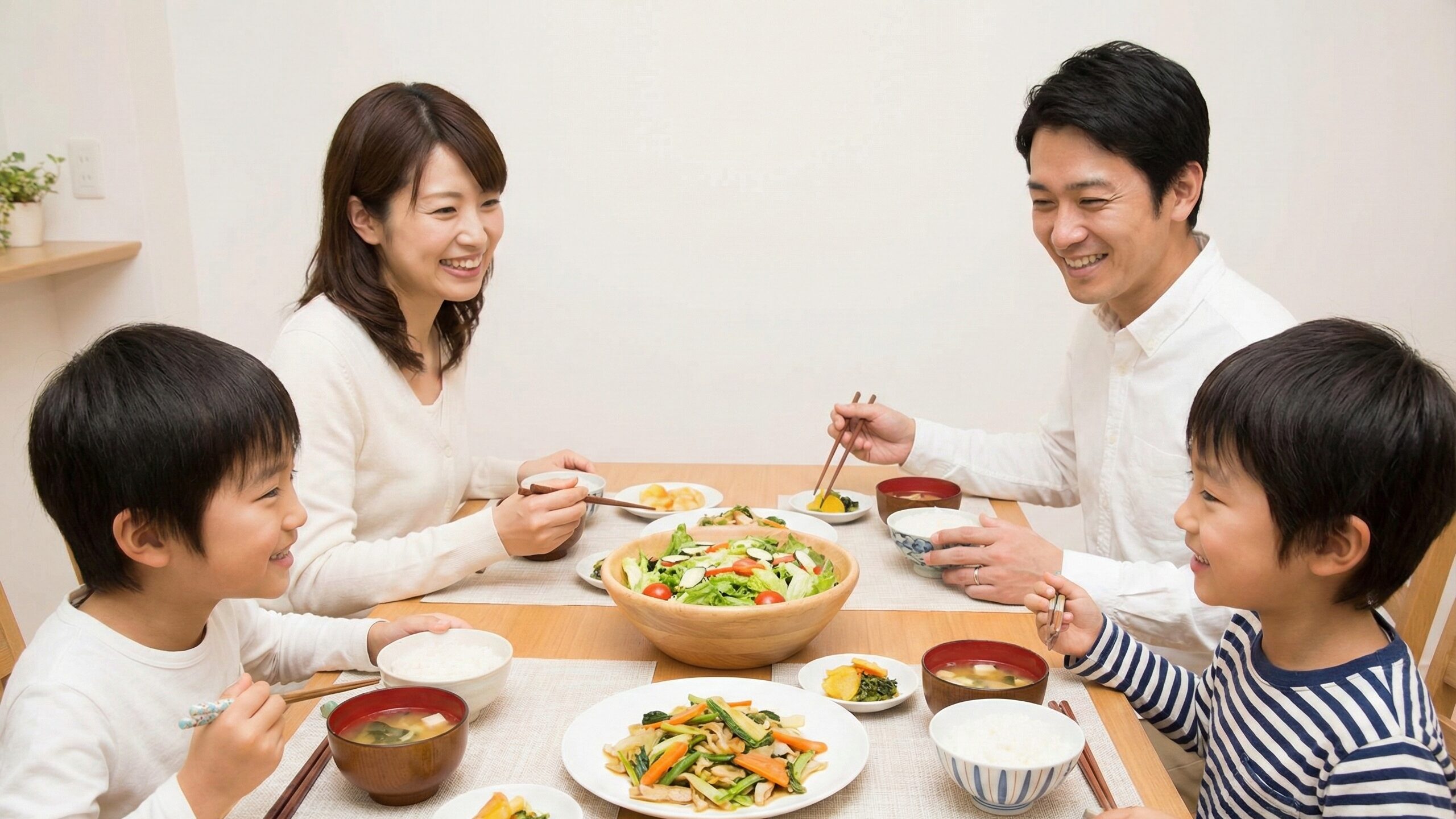 家族全員で彩り豊かなサラダや野菜料理を食べる夕食風景