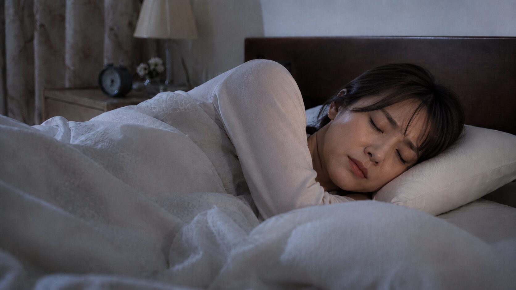 緑茶のカフェインの影響で深夜2時になっても眠れず、ベッドで横になったまま目が冴えている女性。